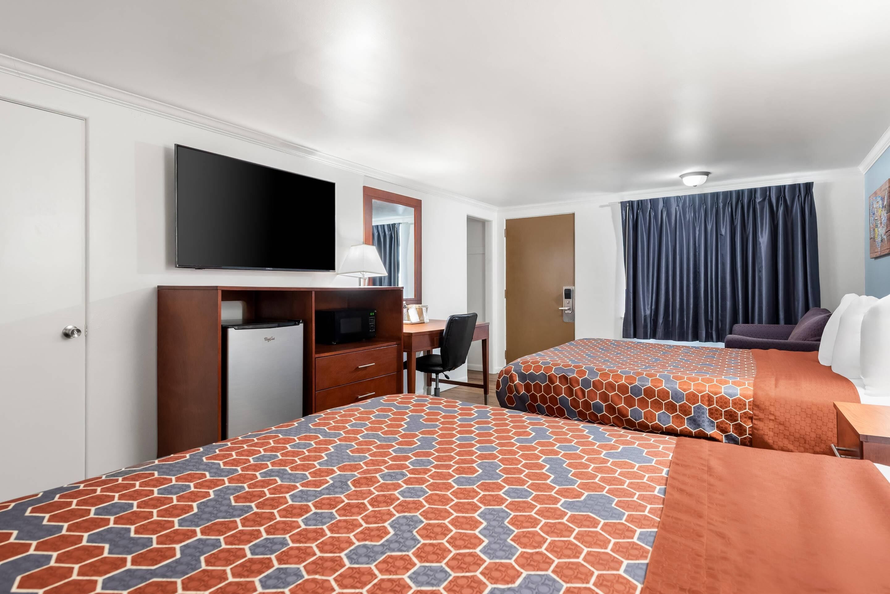 A hotel room with two beds, a desk, a television, and a wardrobe.