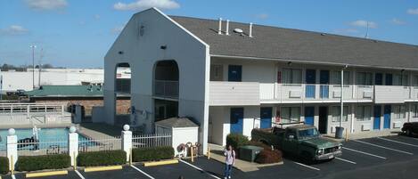 A motel with a pool, a parking lot, and a green truck parked in front.