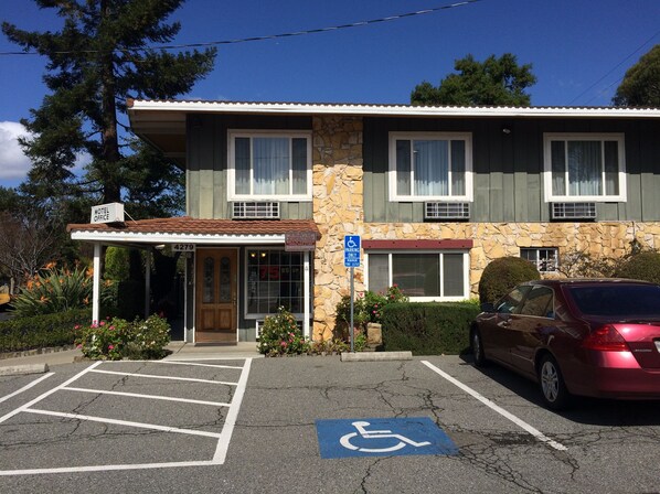 A motel with a stone facade, a covered entrance, and a parking lot with a handicapped parking space.
