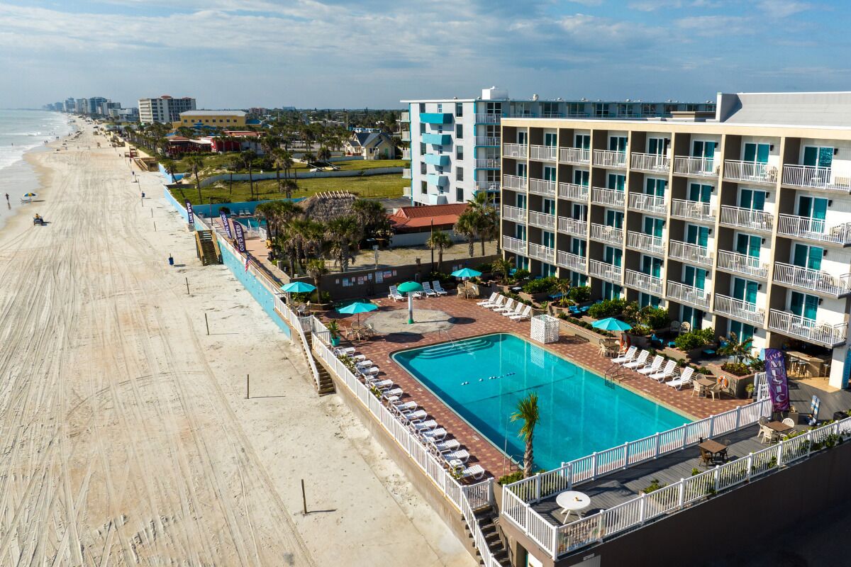 Un hôtel doté d'une piscine, offrant une vue sur la plage et comprenant plusieurs balcons.