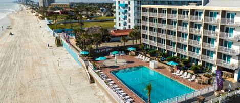 Un hotel con piscina, vistas a la playa y varios balcones.