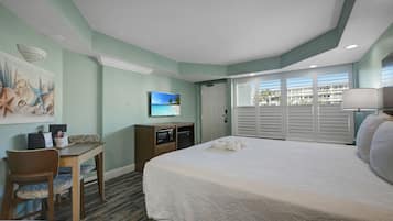 Une chambre d’hôtel avec un lit, un bureau équipé d’un ordinateur, une télévision et une vue sur l’extérieur.