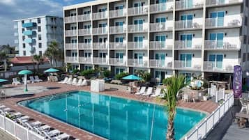 A hotel with a swimming pool, multiple balconies, and outdoor seating areas.
