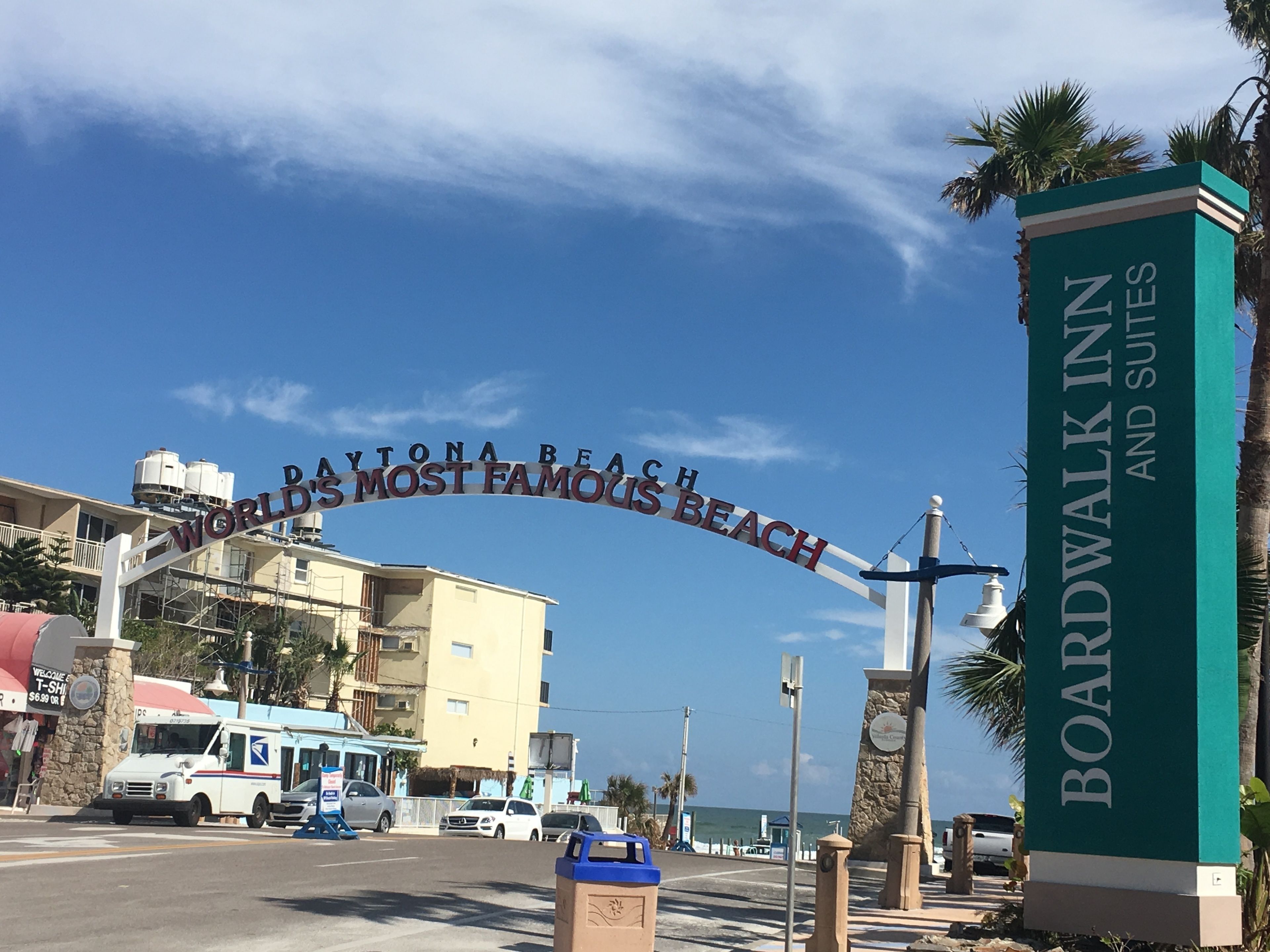 Schild des Boardwalk Inn and Suites mit freiem Blick auf den Ozean und einer Straße mit geparkten Autos.