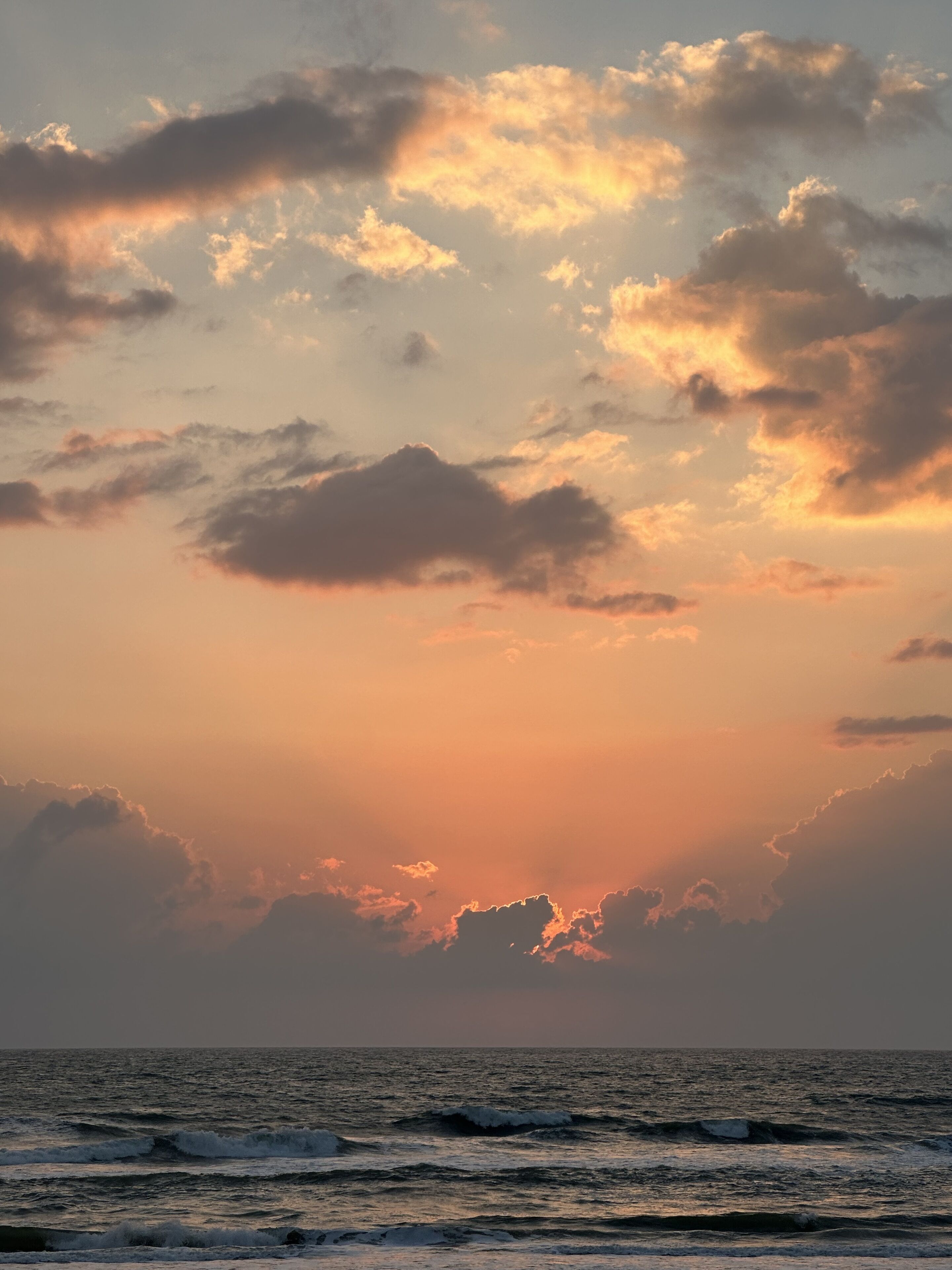 Una puesta de sol sobre el océano con nubes en el cielo.