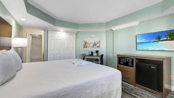 A hotel room with a large bed, a desk with a microwave, a coffee maker, and a TV.