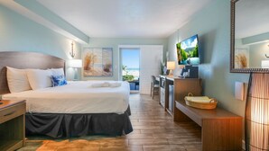 A hotel room with a bed, a desk, a TV, and a view of the sea. - Boardwalk Inn and Suites (Daytona Beach)