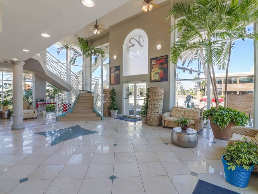 A spacious lobby with a staircase, comfortable seating, and large windows.