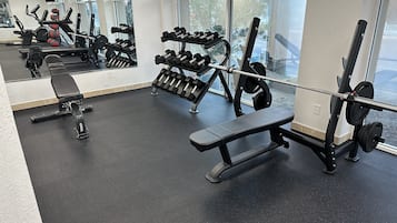 A gym with various exercise equipment, including dumbbells, a bench, and a squat rack.