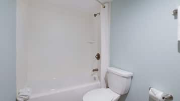 A bathroom with a white bathtub, toilet, and a towel rack with a folded towel.
