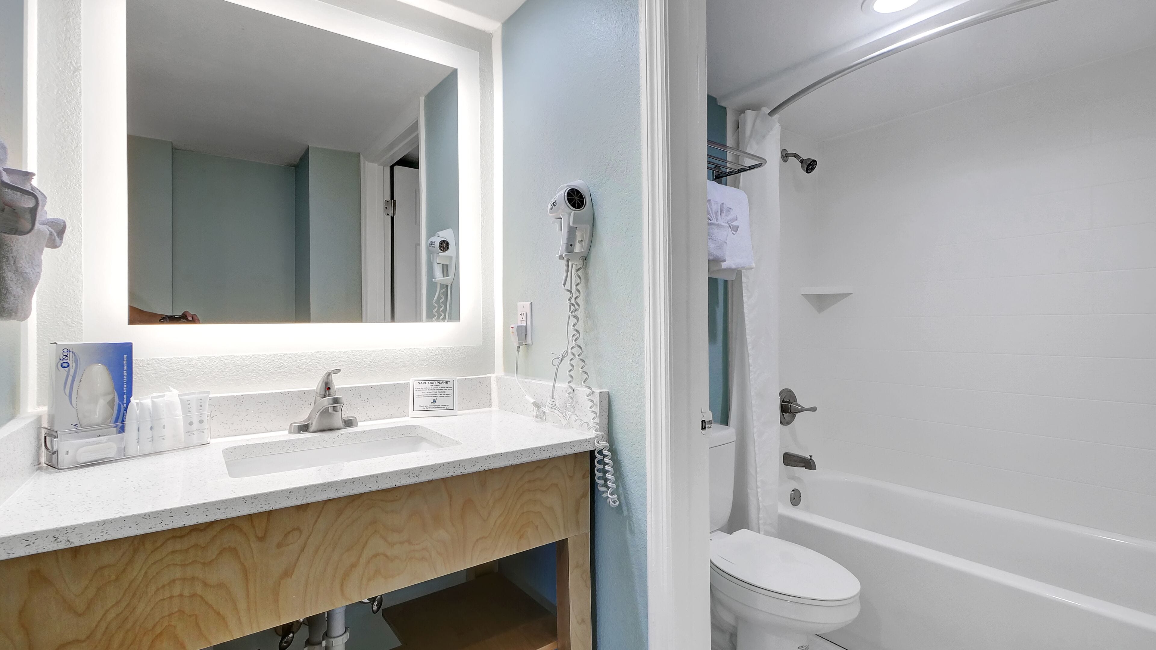 A bathroom with a white sink, mirror, and toilet. There is a shower curtain and a towel rack visible.