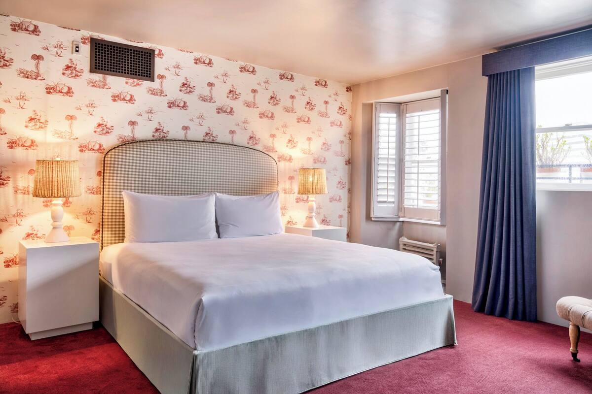 A neatly made bed with white linens, a checkered headboard, and two bedside lamps.