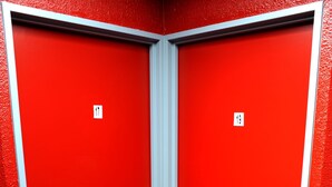 Une porte rouge avec une plaque portant le numéro 19, une poignée en métal et un cadre blanc.