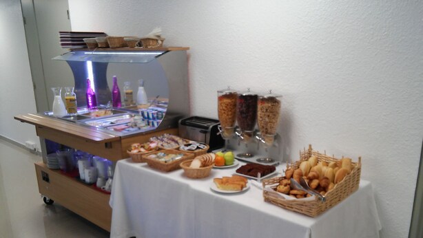 Un buffet proposant une variété de plats et de boissons, notamment du pain, des pâtisseries et des condiments.