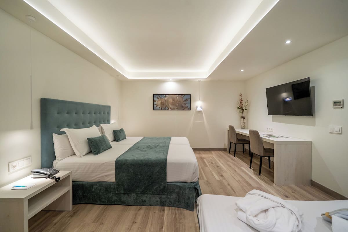 A modern hotel room with a bed, desk, and TV.