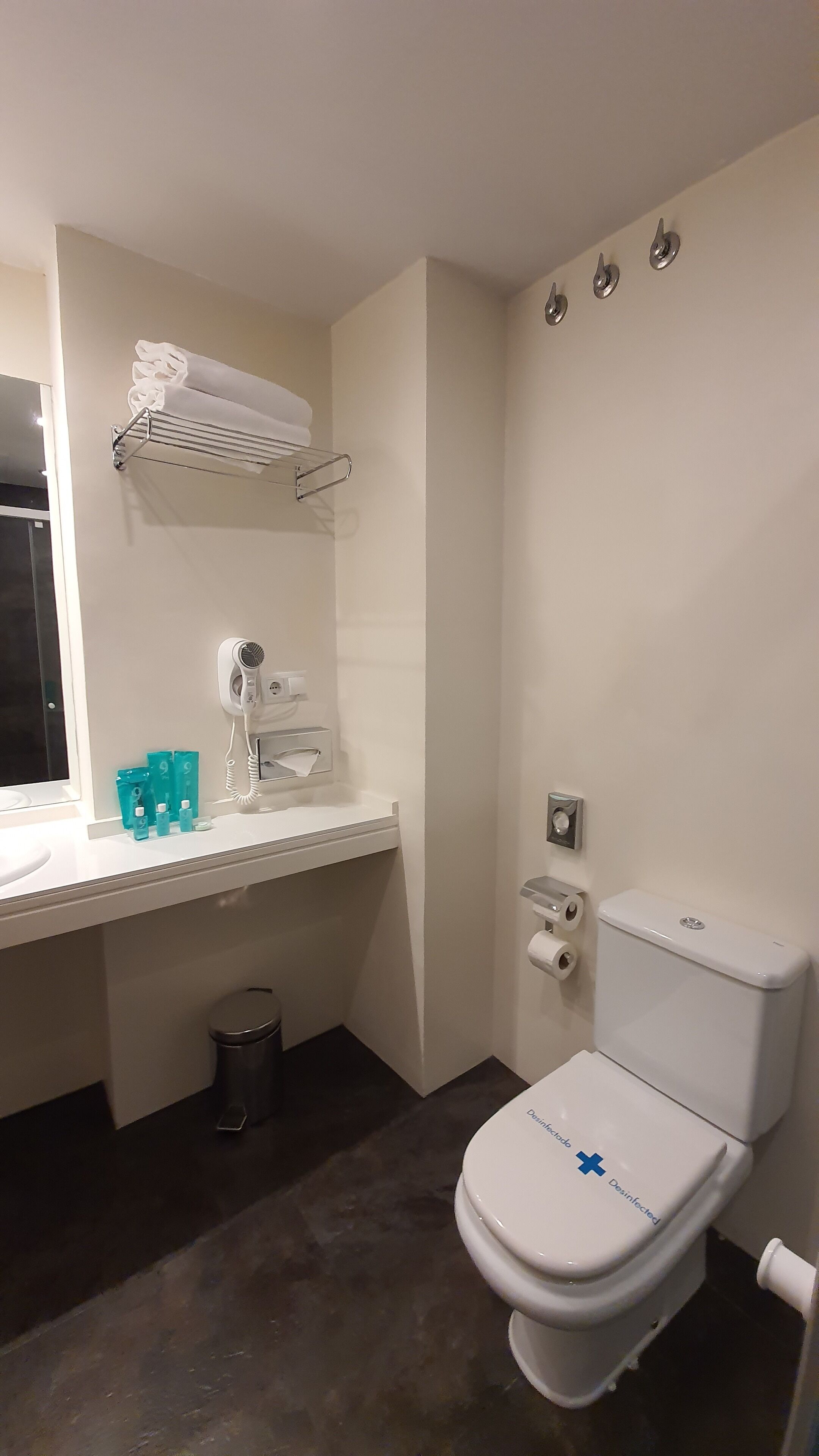 Un baño pequeño y limpio con inodoro, lavabo, toallero y un cubo de basura.