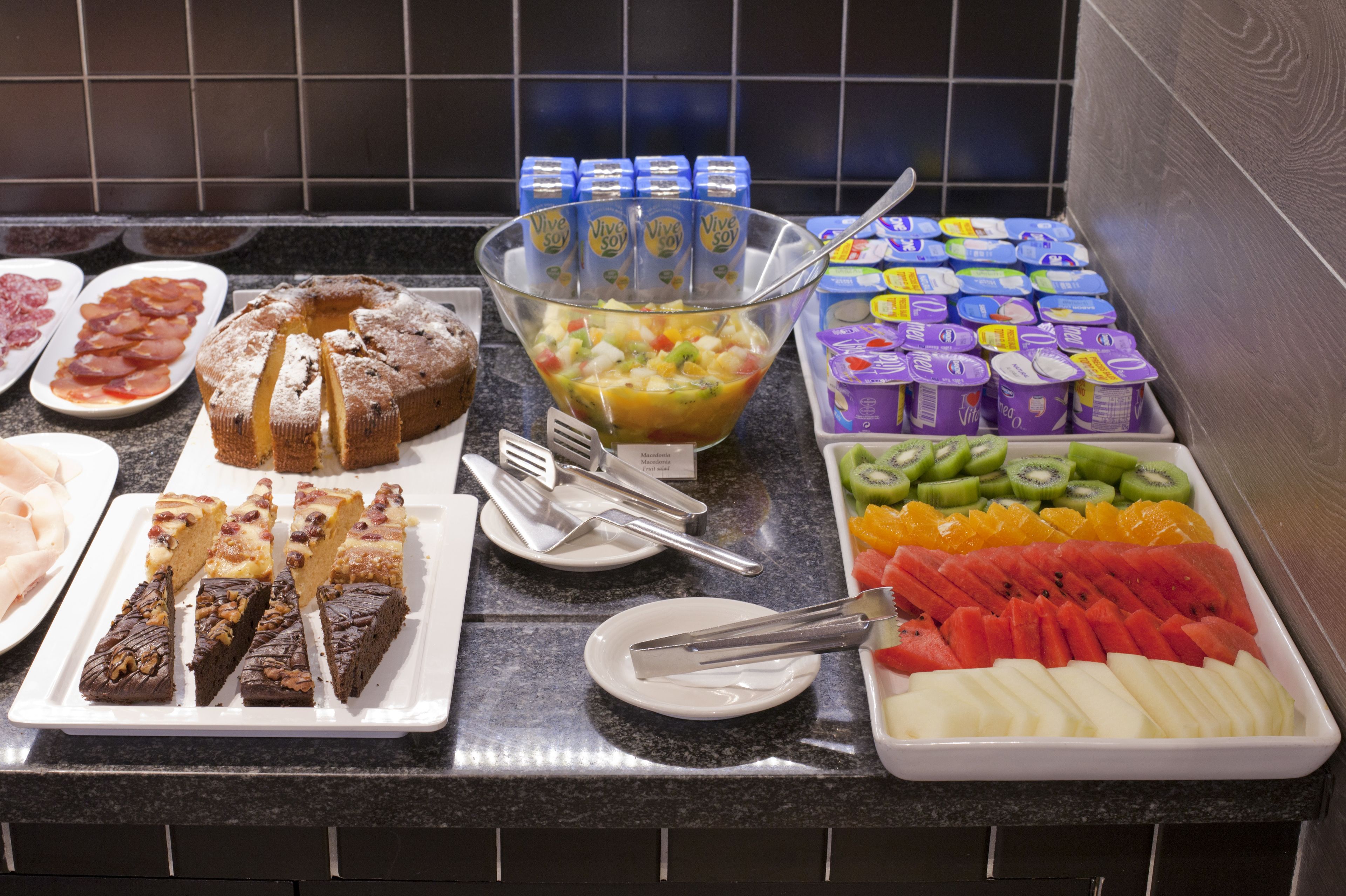 Un bufé con diversos alimentos, incluyendo frutas, verduras y postres.