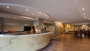 A hotel reception area with a marble counter, a large map, and a seating area with sofas.