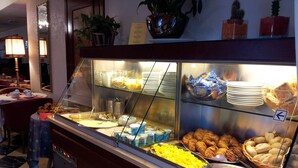 Un buffet proposant une variété de plats, notamment des pâtisseries, des viandes et des salades.