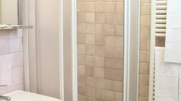 A bathroom with a glass-enclosed shower, a white sink, and a towel rack.