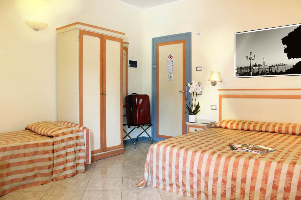 Een hotelkamer met twee enkele bedden, een garderobe, een bureau en een stoel.