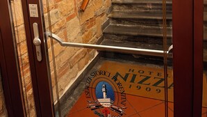 En hotellentréd med en skylt som visar texten ”HOTEL NIZZA 1909” och en trappa som leder in.