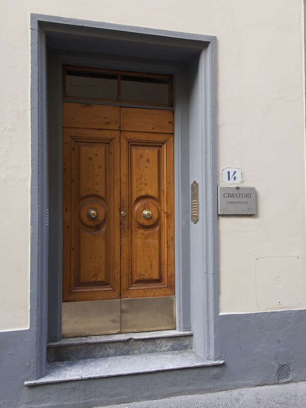 A double wooden door with a metal handle, a small sign above it, and a stone ledge below. - B&B Cimatori (Florence)