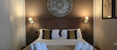 A hotel room with a large bed, two bedside lamps, a round wall decoration, and a chair.
