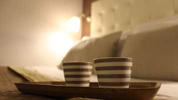 Dos tazas a rayas sobre una bandeja en una cama, con un almohadón y una lámpara al fondo.