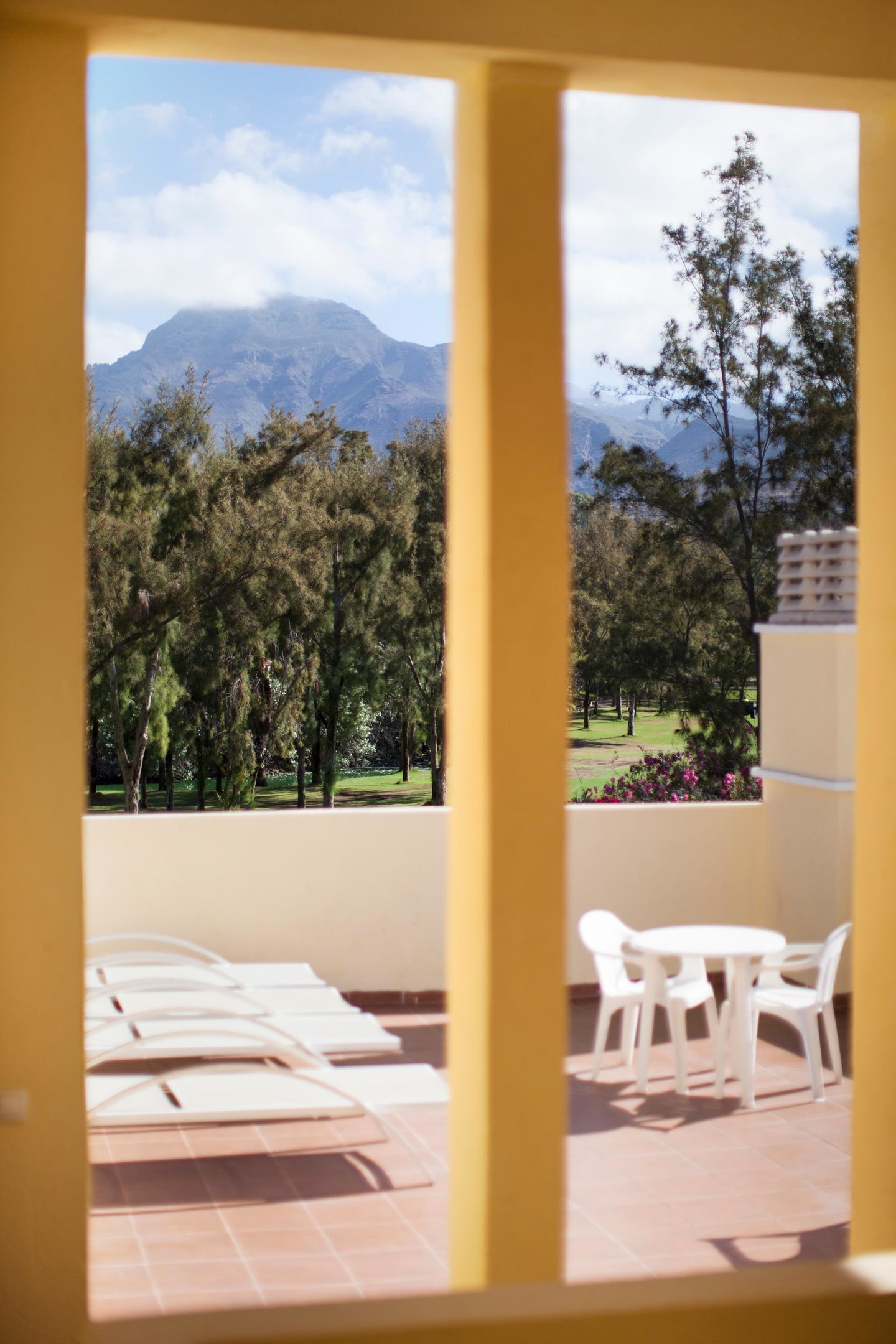 Un balcon avec vue sur une montagne, des arbres et un espace verdoyant.