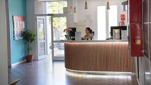 A reception area with a wooden reception desk, a potted plant, and a receptionist. - Coral Compostela Beach Golf (Arona)