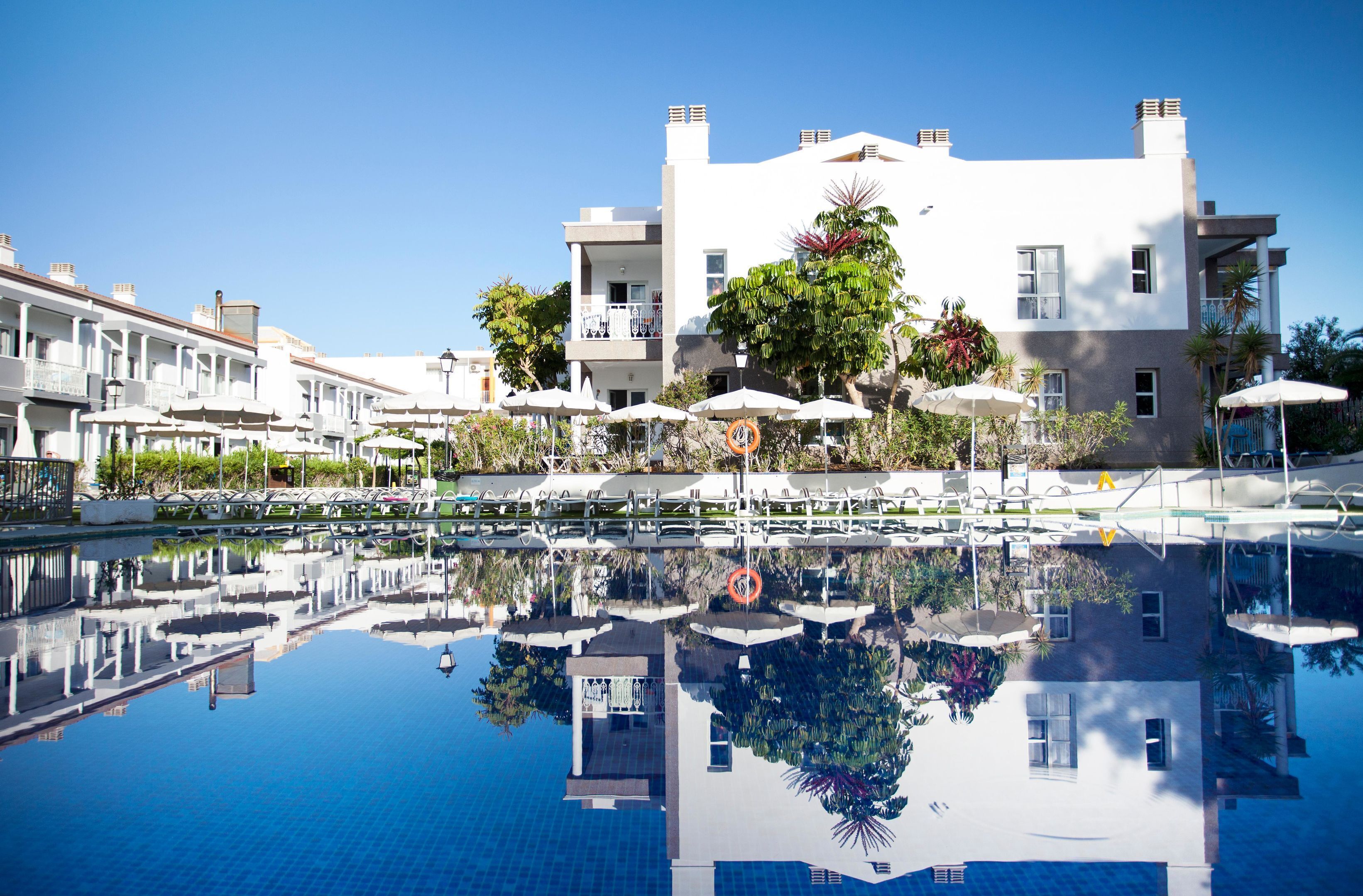 Ein Hotel mit Schwimmbad, Liegestühlen und Sonnenschirmen.