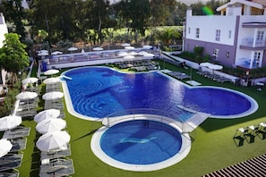 Una piscina al aire libre, sillones reclinables de piscina
