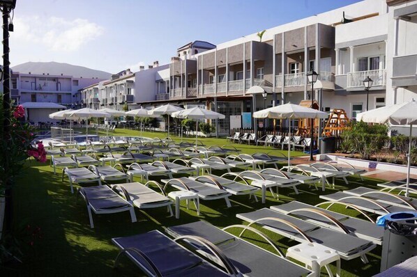 A hotel courtyard with sun loungers, umbrellas, and a pool area. - Coral Compostela Beach Golf (Arona)