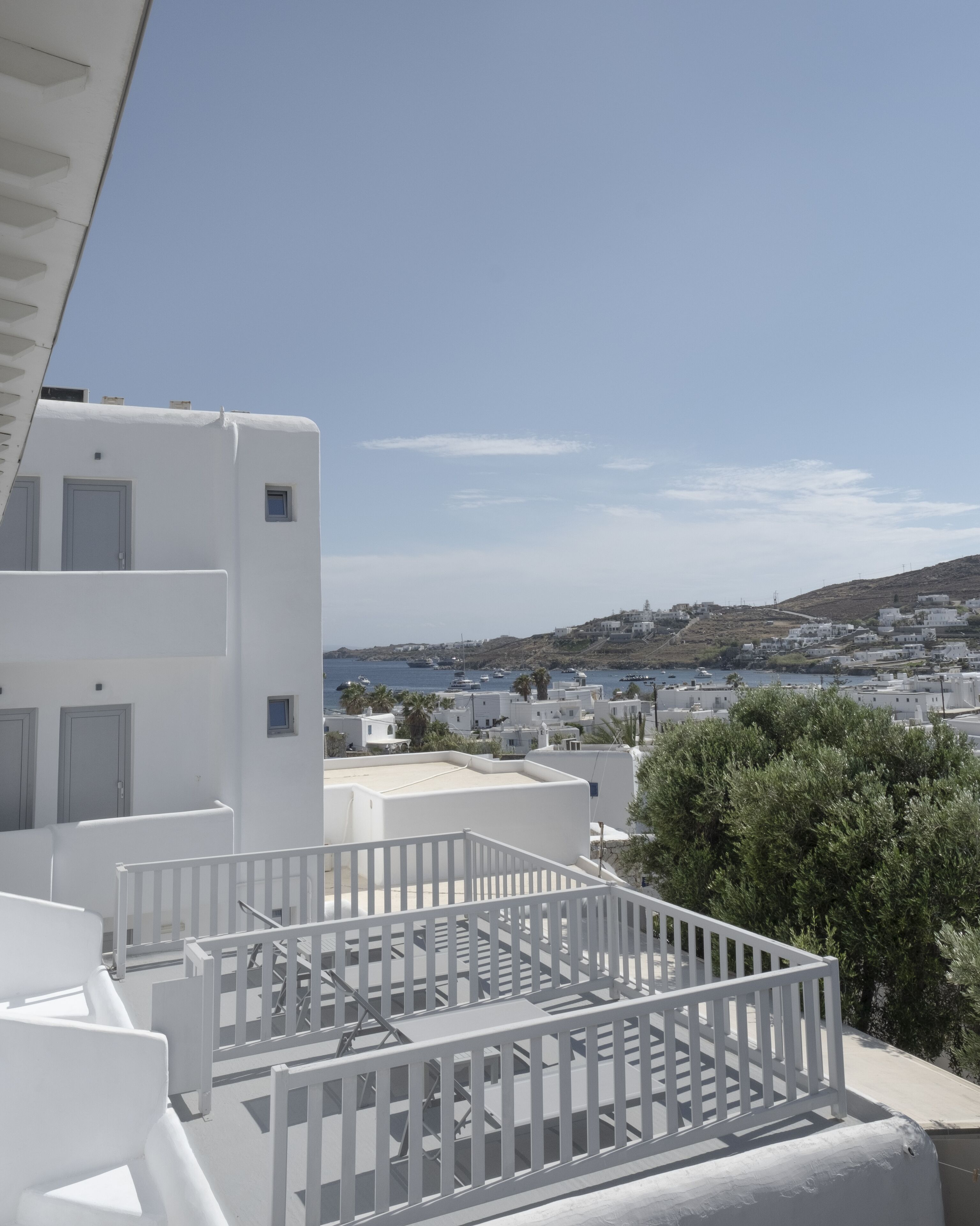 A white building with a balcony overlooking a coastal town.