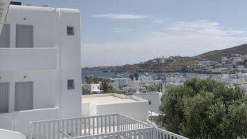 A white building with a balcony overlooking a coastal town.