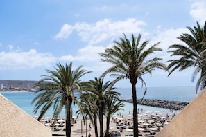 A beach view with palm trees, umbrellas, and beach chairs. - Coral Compostela Beach (Arona)