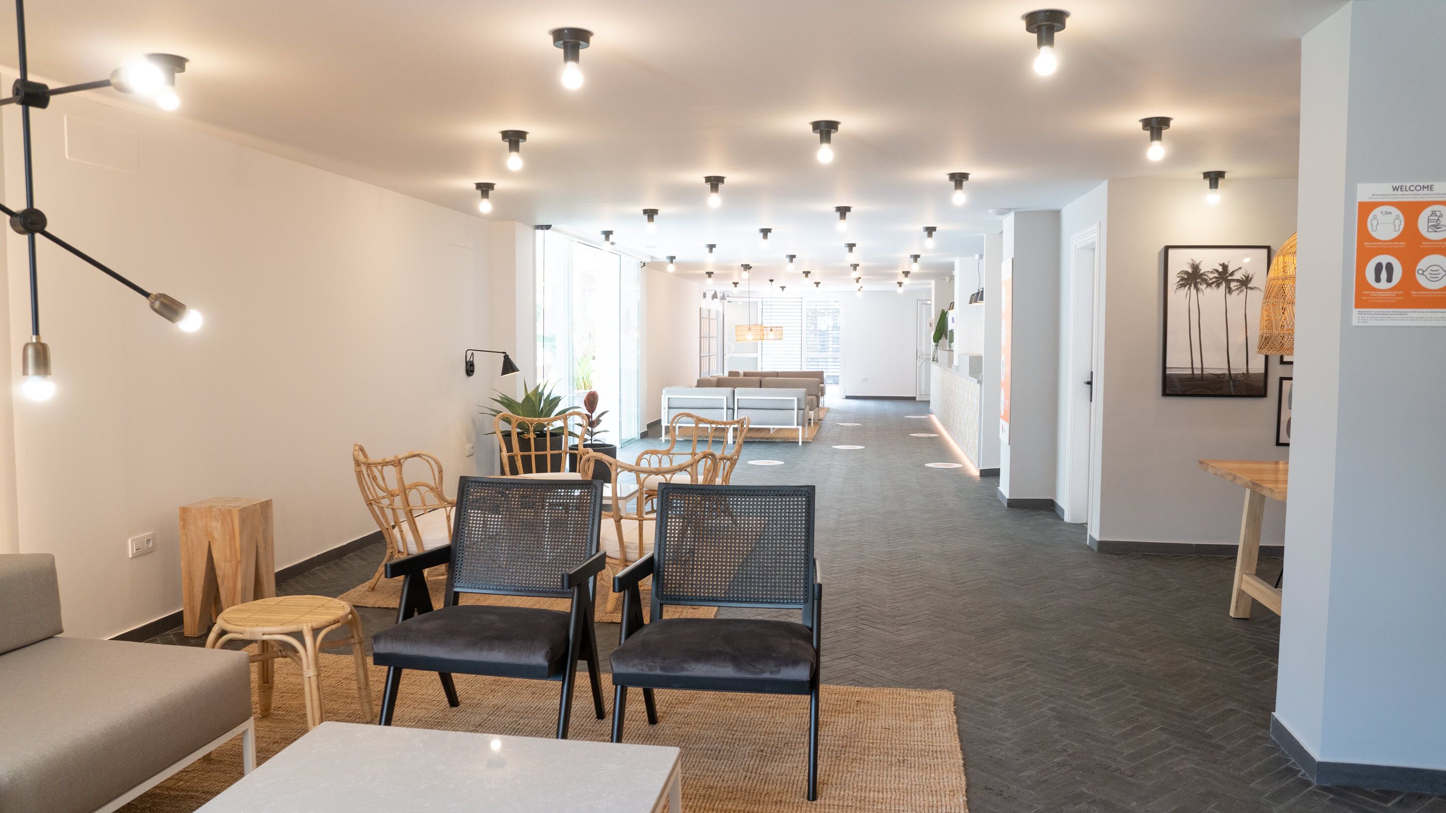 A modern interior with a long reception area, seating arrangements, and a central light fixture.