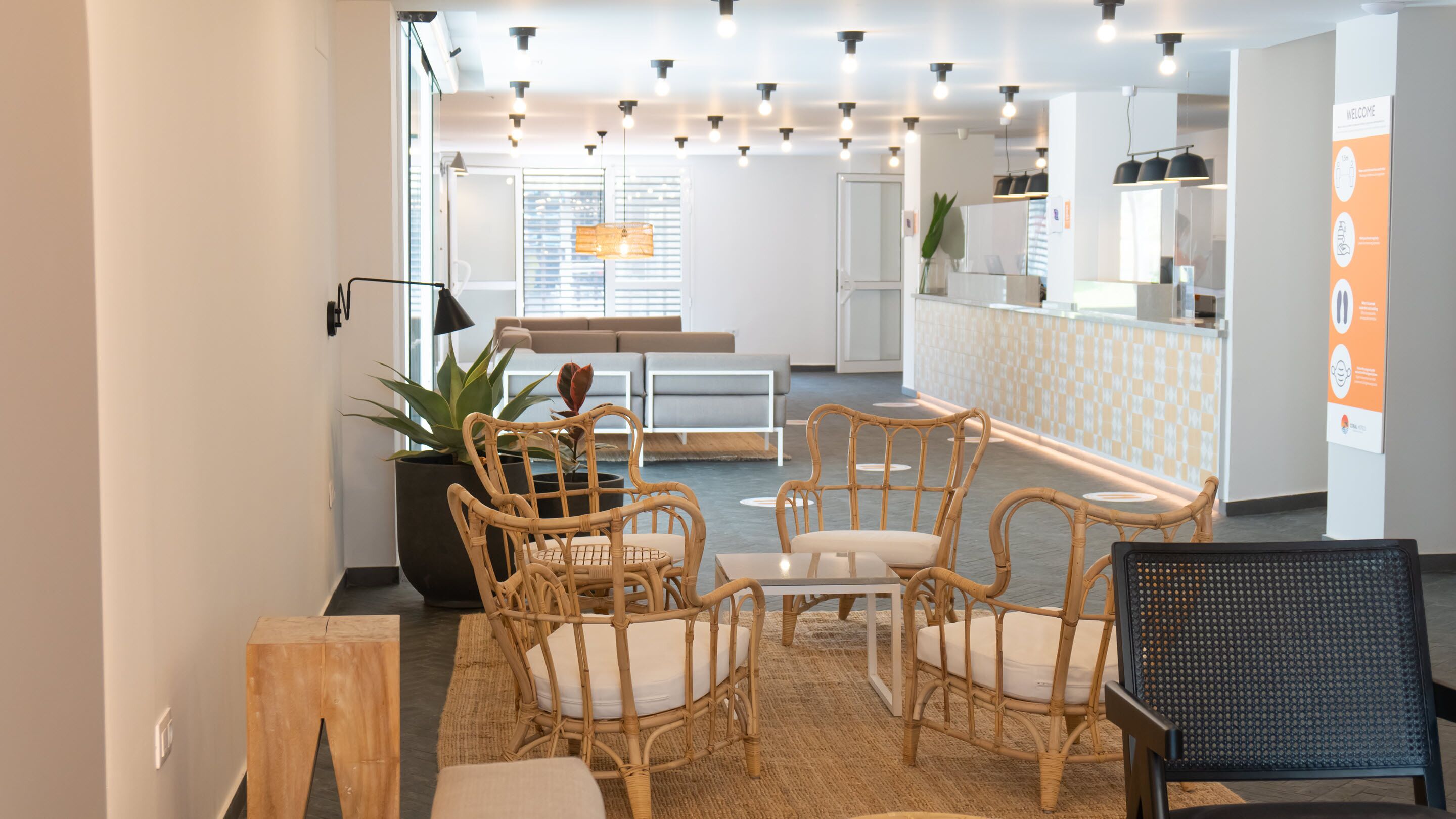 A modern interior with wicker furniture, a kitchen area, and a reception desk.
