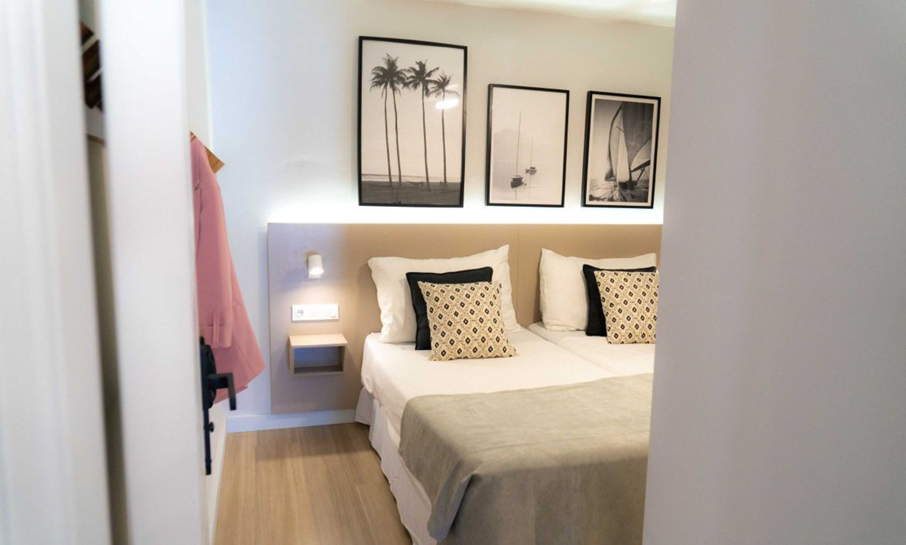A neatly arranged bedroom with a bed, bedside tables, and wall-mounted artwork.
