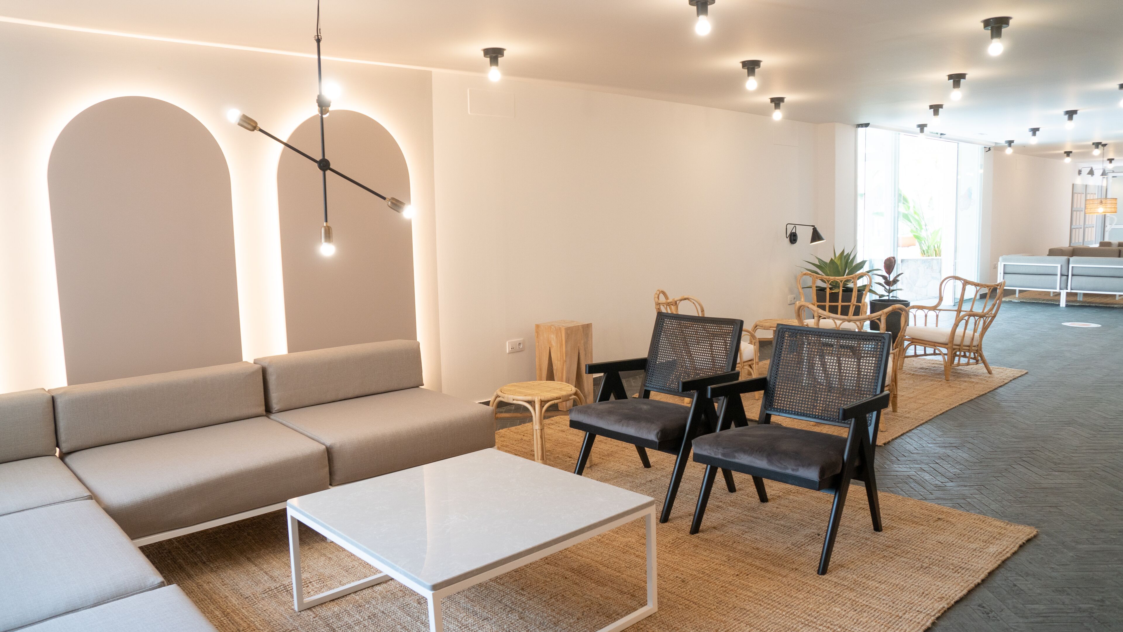 Una sala moderna con un sofá, sillas, una mesa de centro y un comedor con una mesa y sillas.
