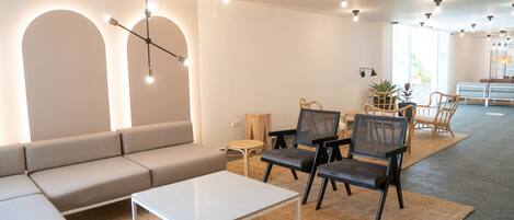 Una sala moderna con un sofá, sillas, una mesa de centro y un comedor con una mesa y sillas.