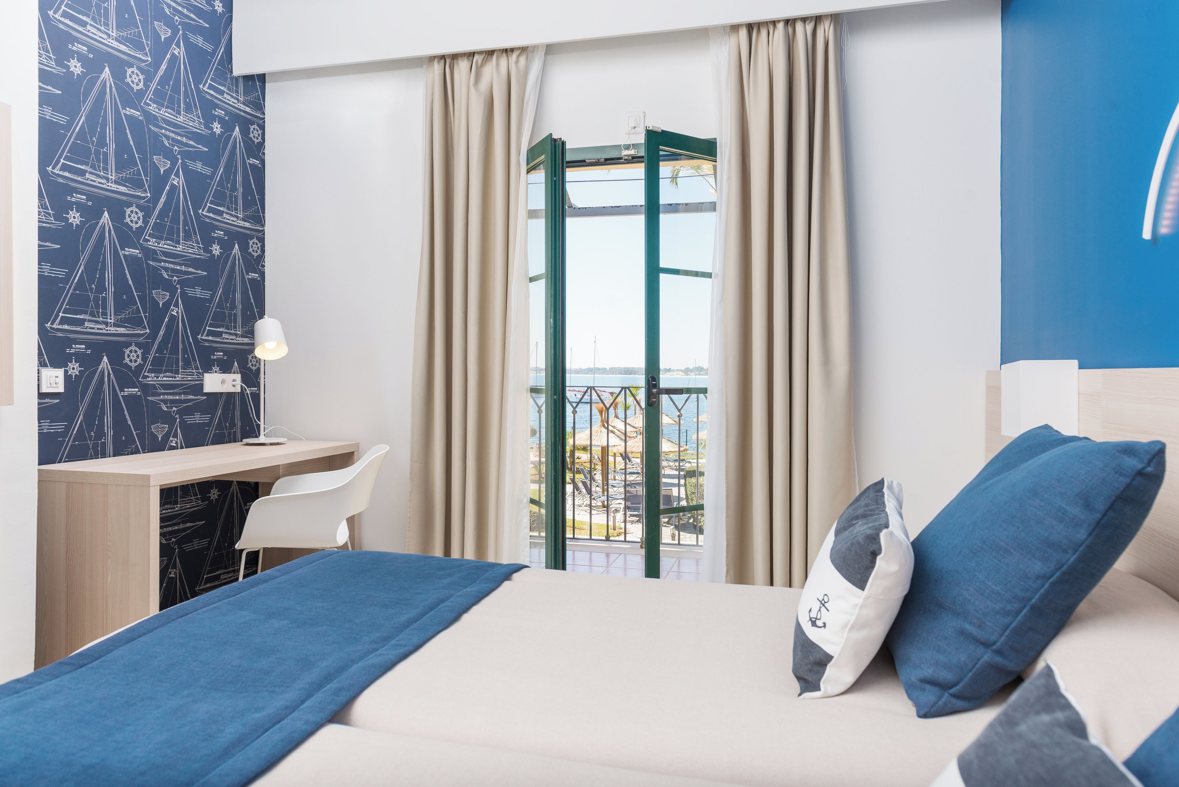Habitación de hotel con cama, escritorio, silla y vistas al exterior.