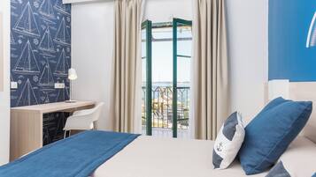 Habitación de hotel con cama, escritorio, silla y vistas al exterior.
