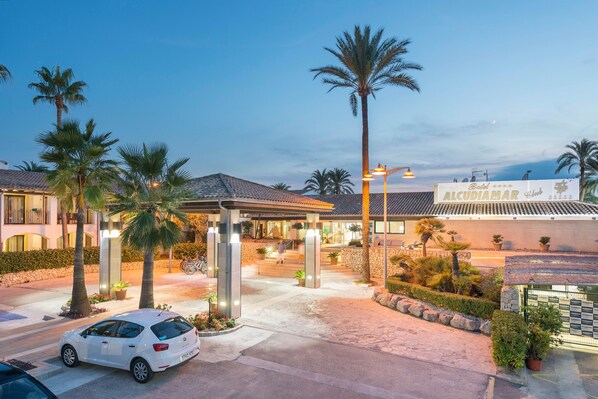 A hotel entrance with a covered walkway, palm trees, and a sign reading "Alcudia Mar Club". - Alcudiamar Marina Residence (Alcúdia)