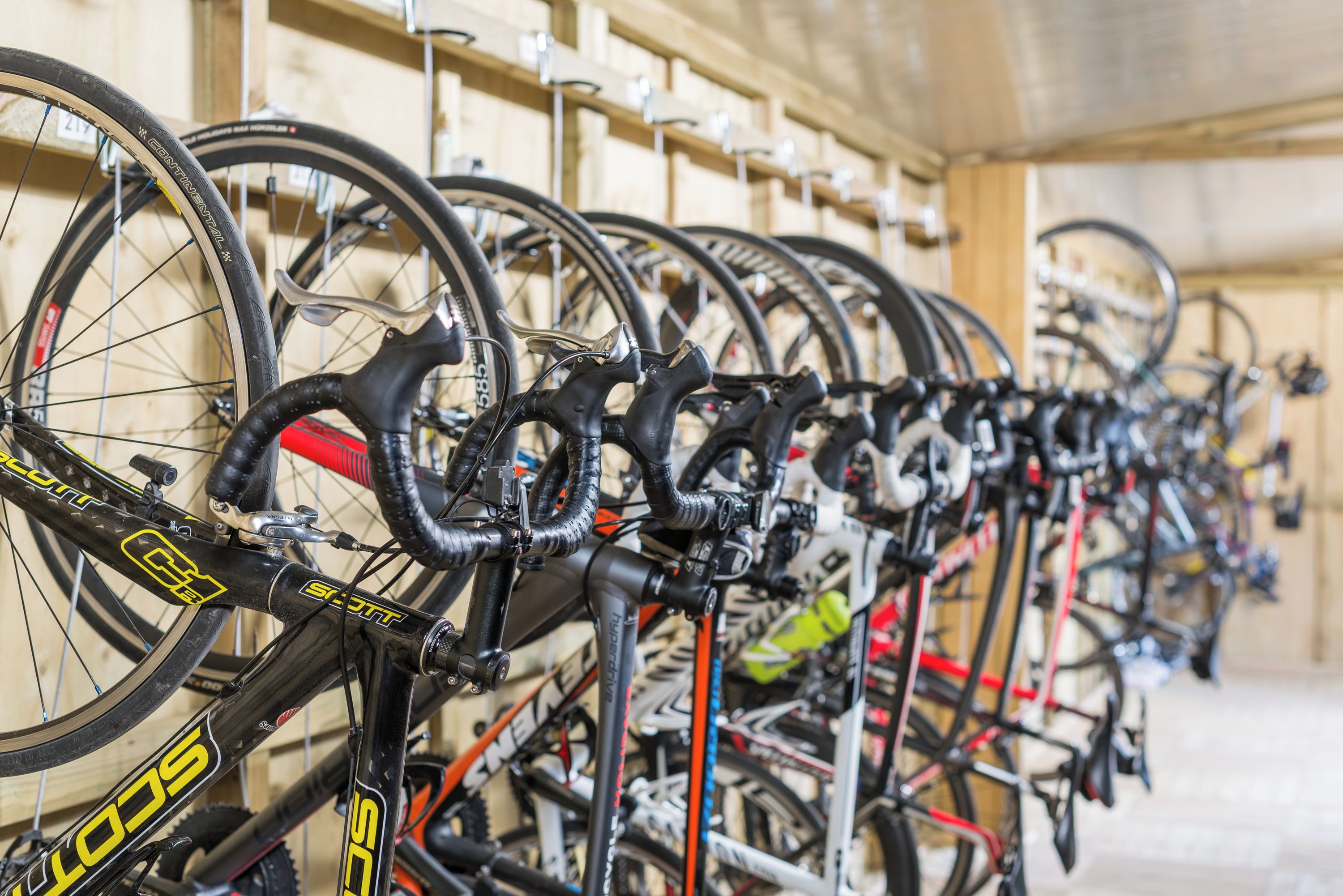 Varias bicicletas estacionadas en un espacio interior con paredes de madera.