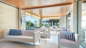 A modern hotel lobby with a wooden ceiling, large windows, and a seating area with sofas and armchairs. - Alcudiamar Marina Residence (Alcúdia)