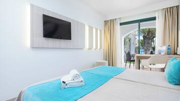 A hotel room with a bed, a TV mounted on the wall, a table with chairs, and a view of the outdoors.
