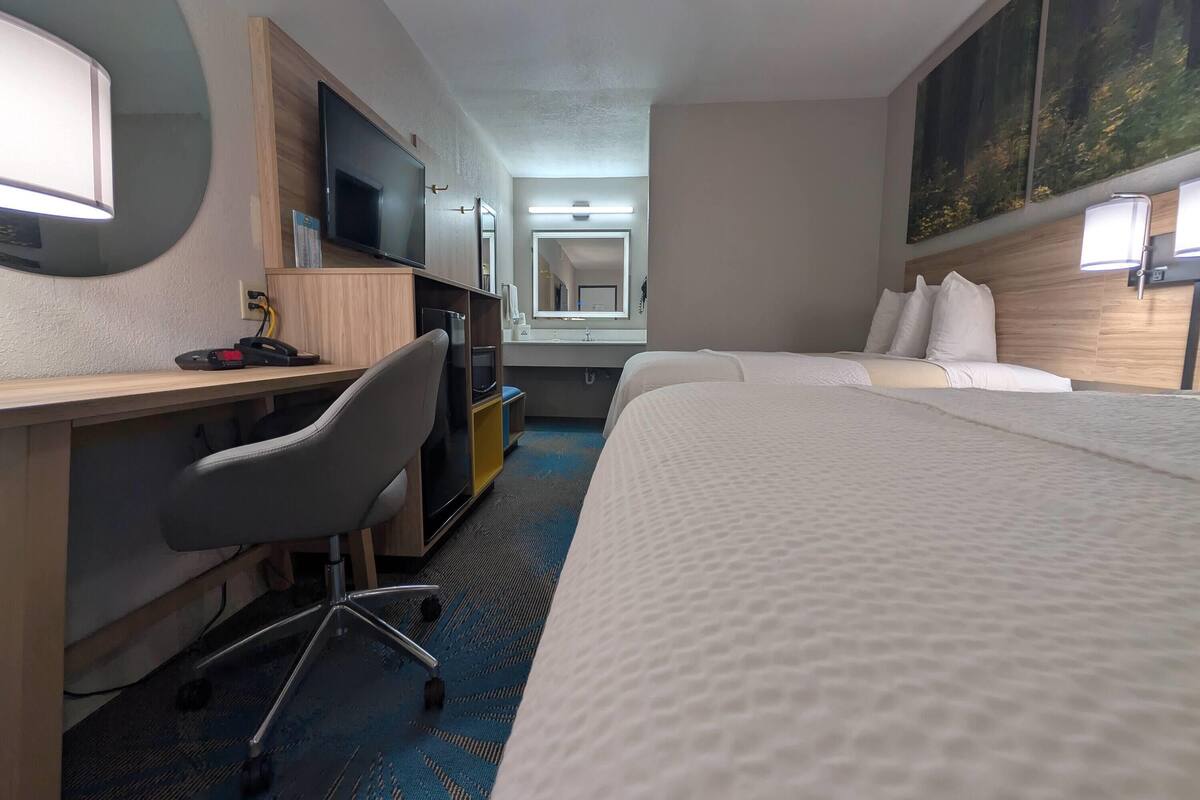 Ein Hotelzimmer mit Schreibtisch, Stuhl, Bett und einem großen Spiegel.
