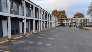 Un motel con varias habitaciones, un estacionamiento y un cartel con el nombre.